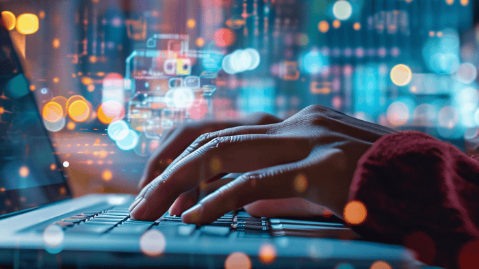 a pair of women's hands typing on a laptop keyboard with an abstract bokeh-effect background