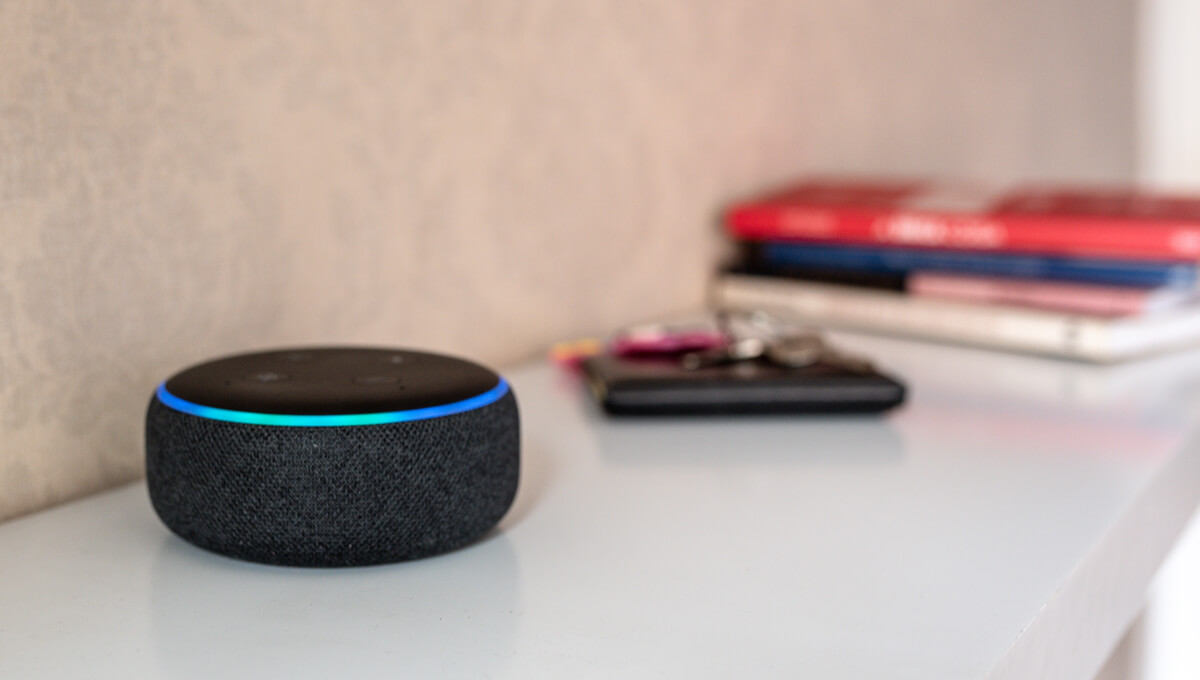 a digital voice assistant device sitting on a bookshelf in someone's home