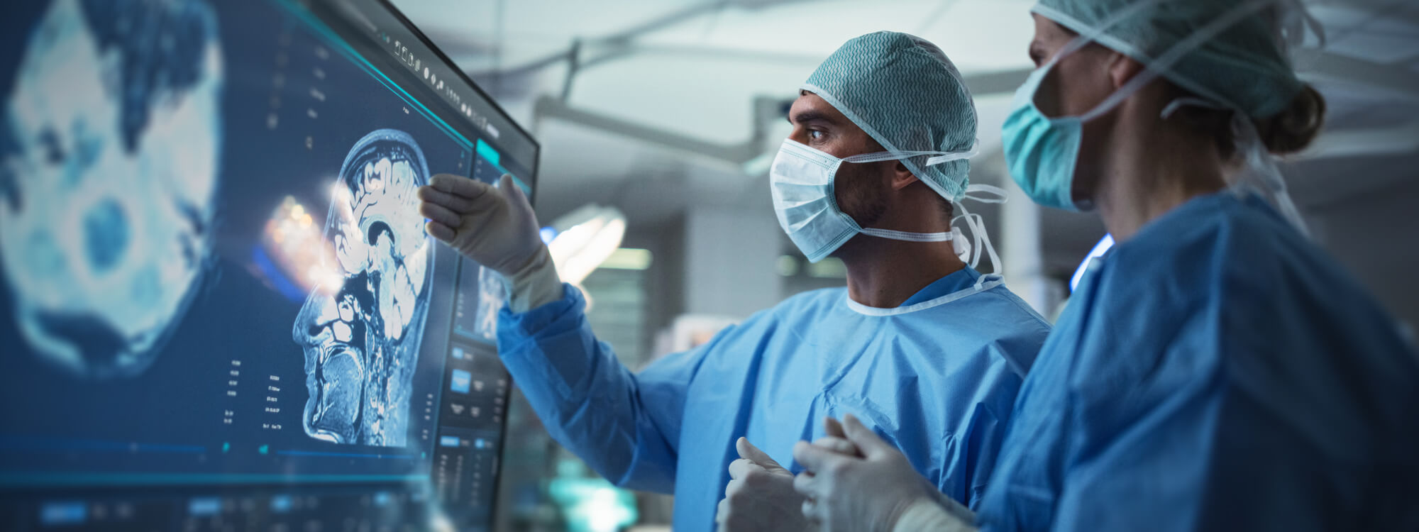 two brain surgeons analysing MRI results on a large monitor