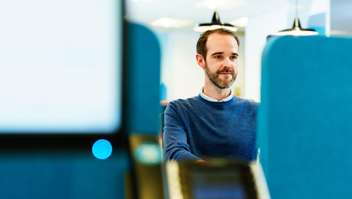 a man focusing on his computer screen in a bright, modern office space