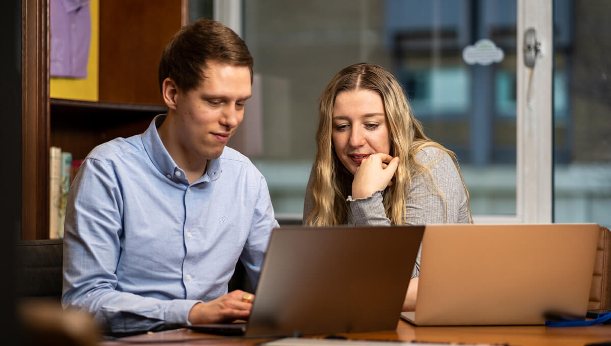 an AI advertising consultant showing a customer how to access ads statistics on a laptop
