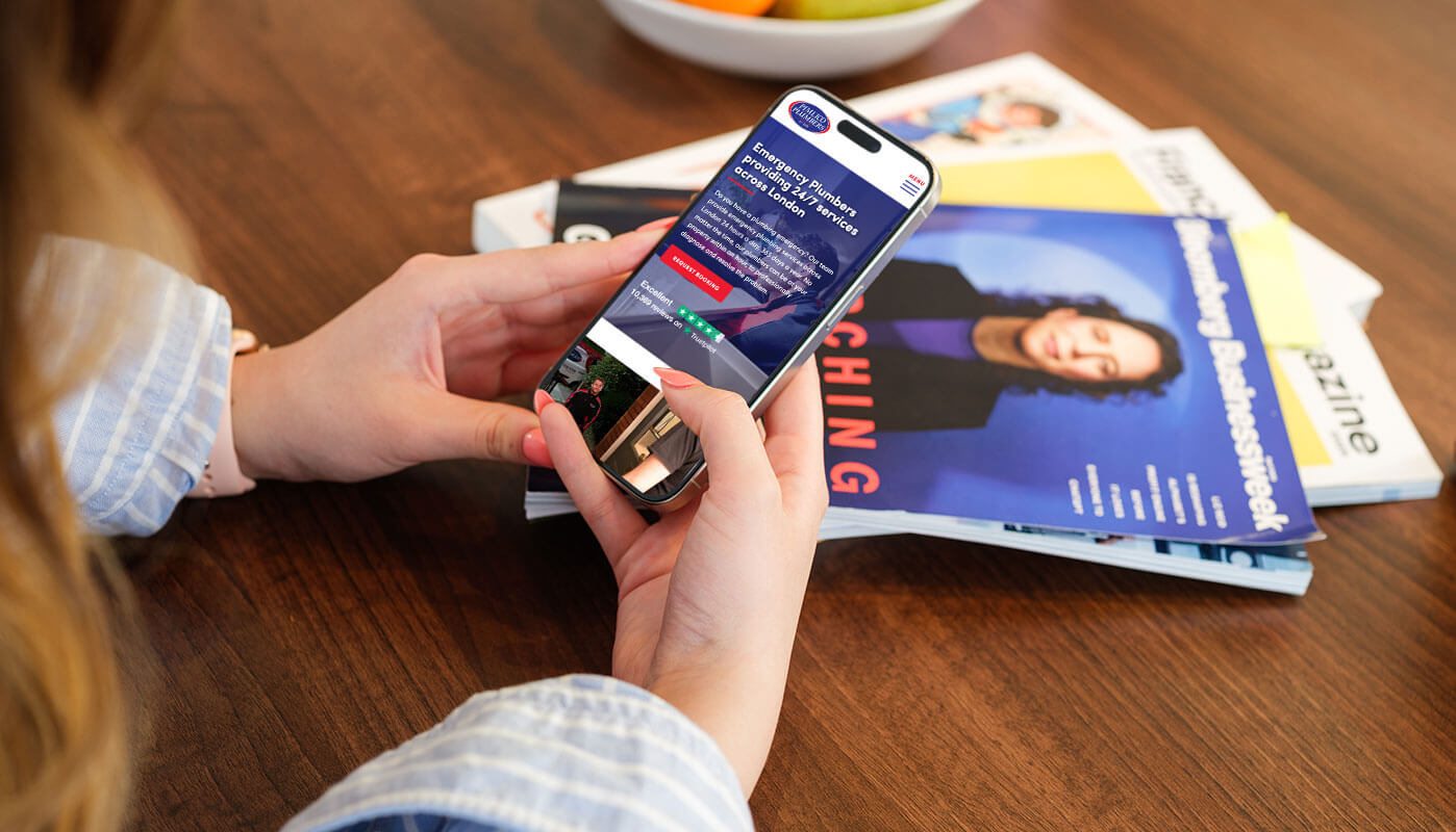 A woman holding a mobile with the new Pimlico Plumbers website.