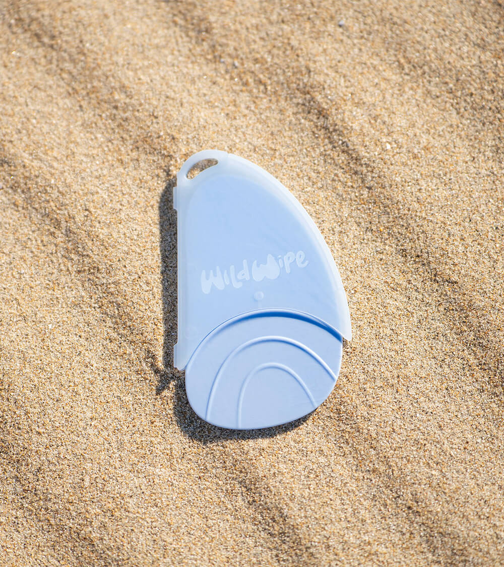 A Wild Wipe reusable wiper in its case placed on sand.