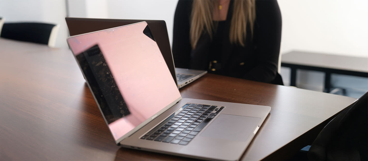 An open laptop on a large meeting room desk.