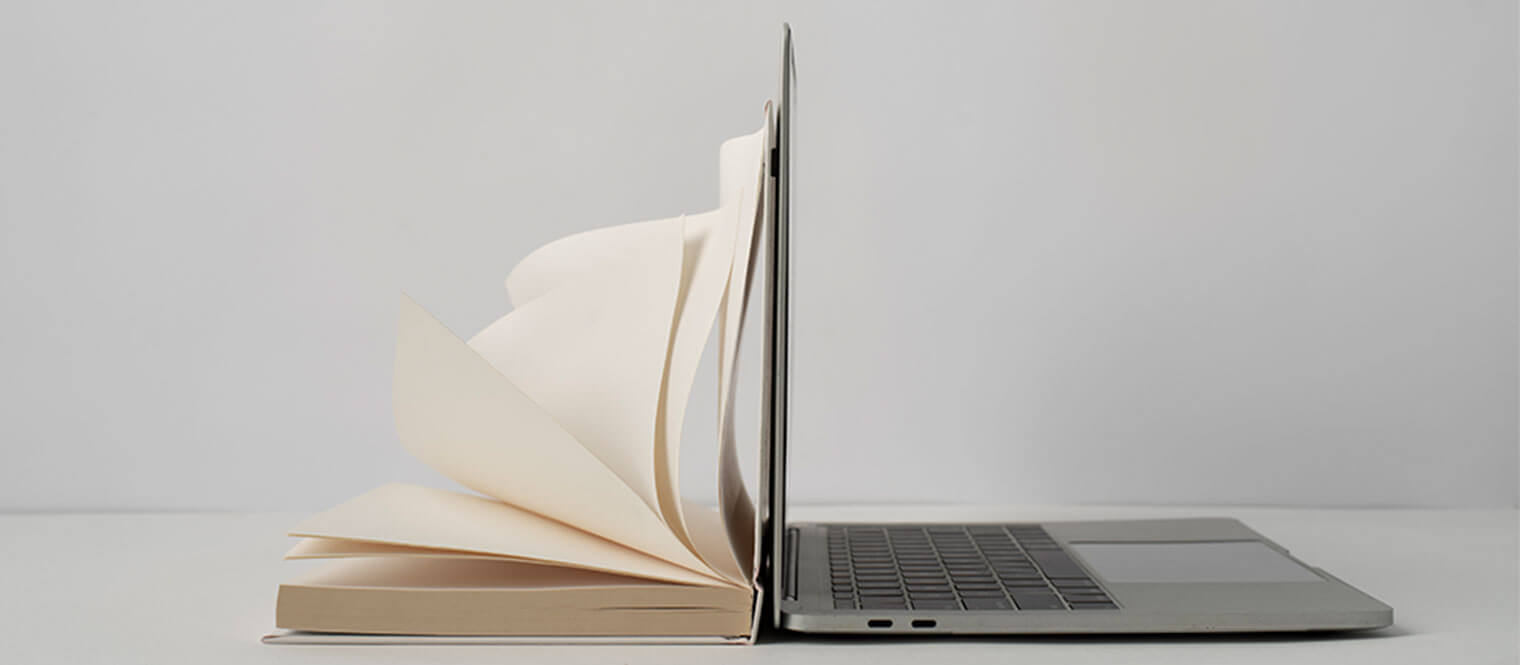 A book open next to a laptop.