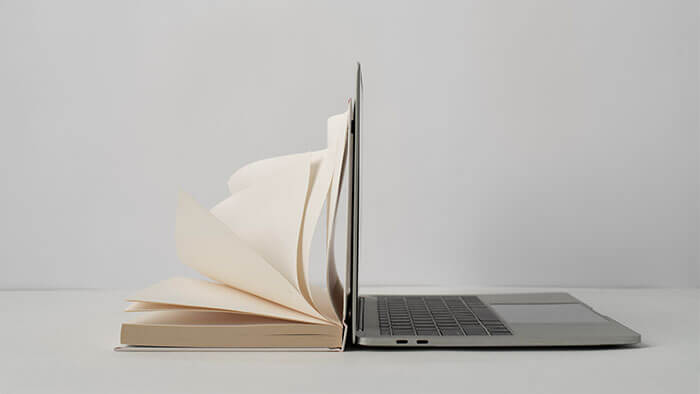 A book open next to a laptop.