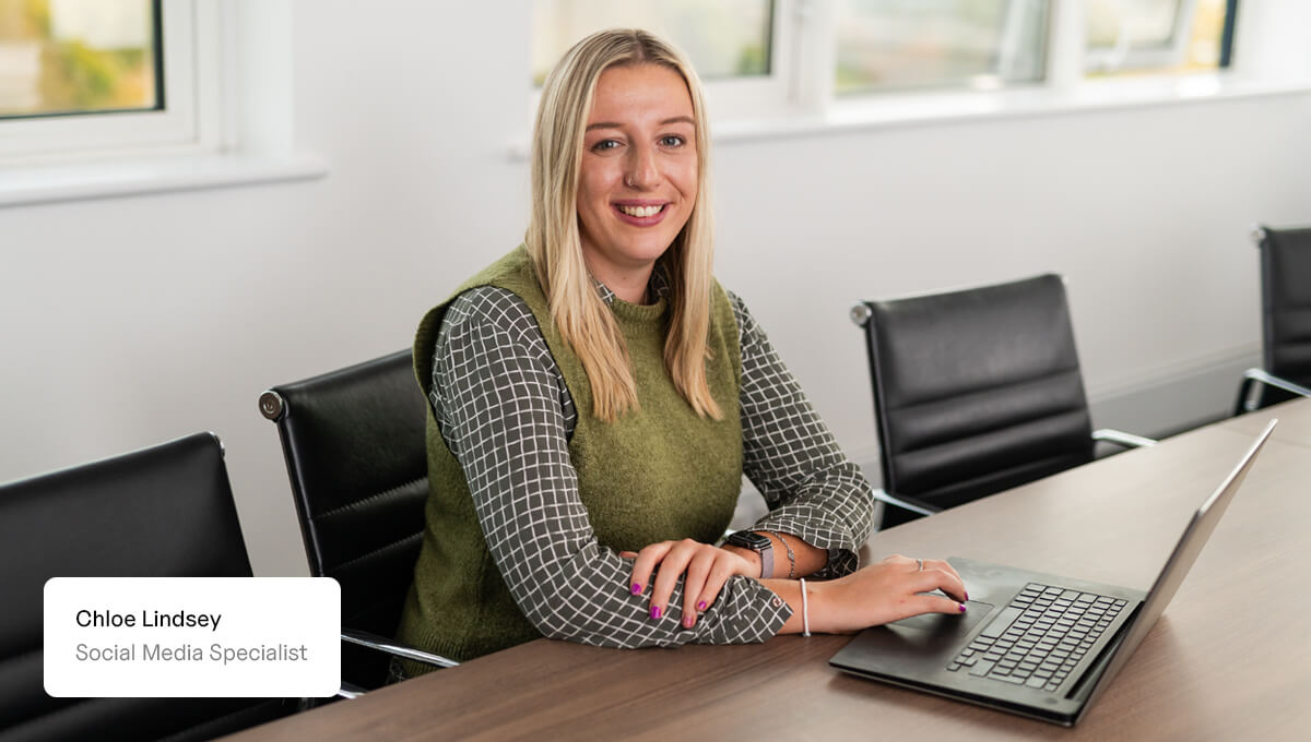 Social Media Specialist, Chloe Lindsey, posing for the camera with her laptop