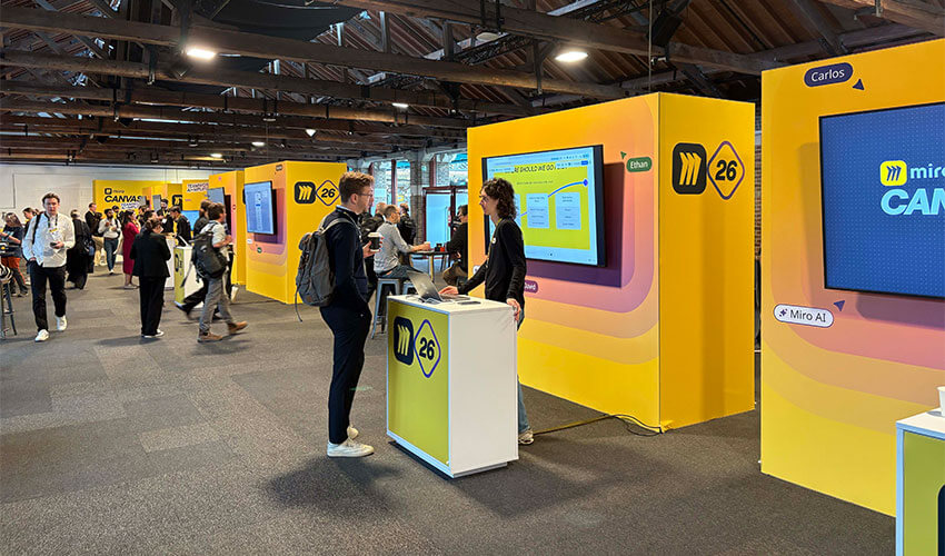 People talking at a Miro event stand.