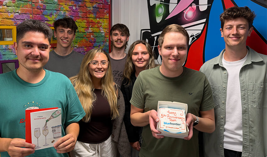 The Blue Frontier team with cards and a DeskLodge anniversary cake.