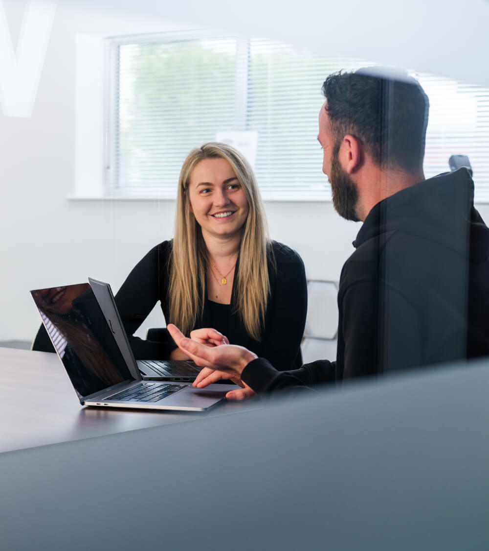 two colleagues have a conversation in a light and airy boardroom