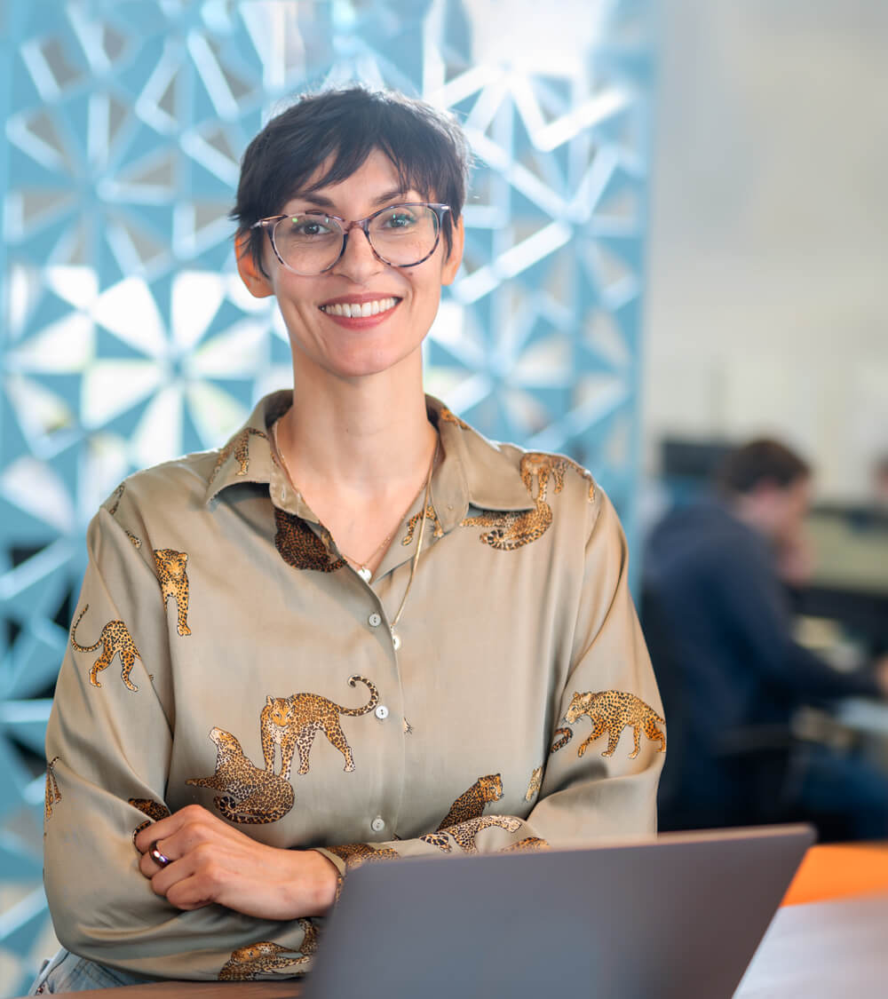 a woman stands proudly in front of the camera with her laptop