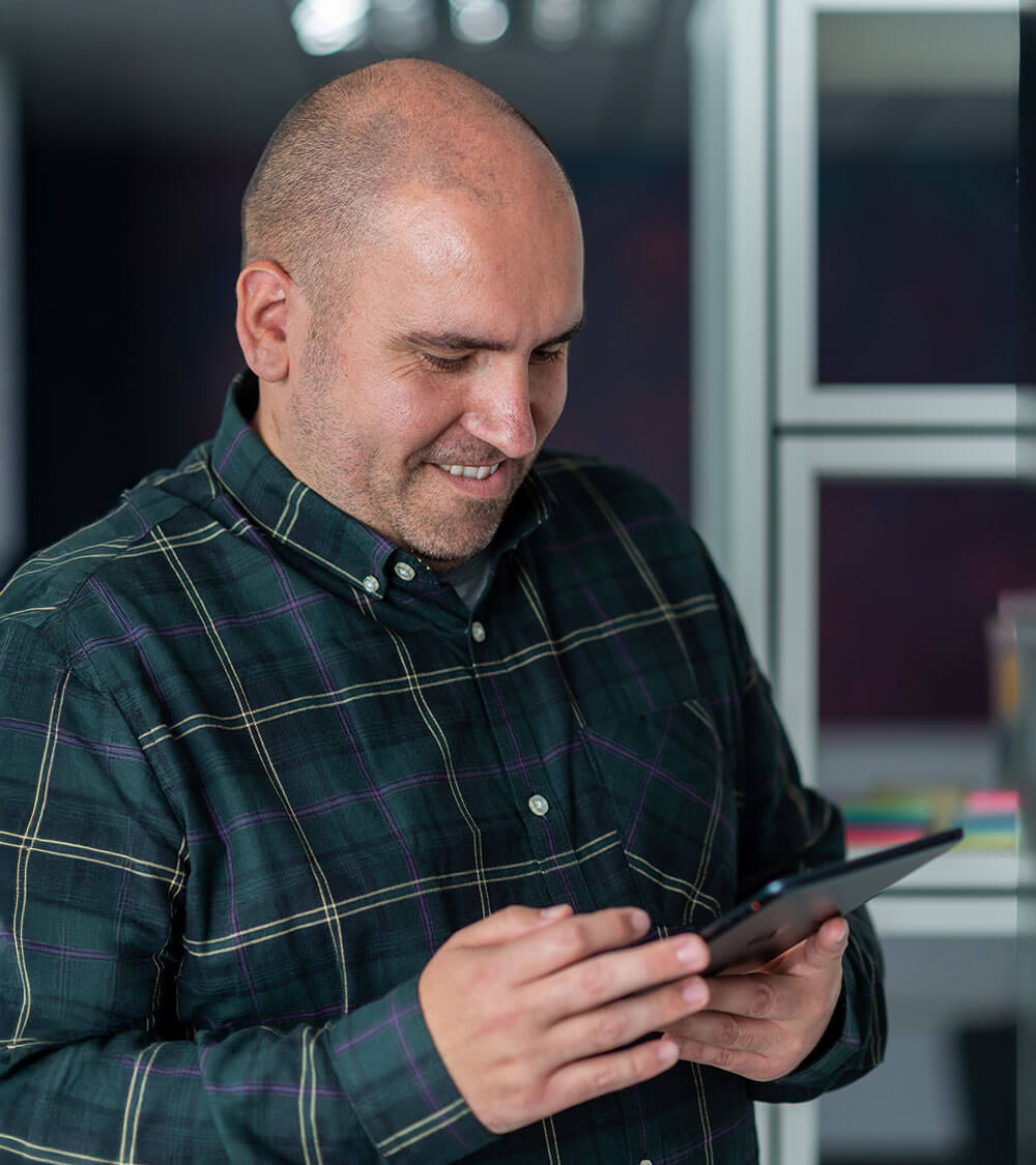 a man holds a tablet whilst smiling