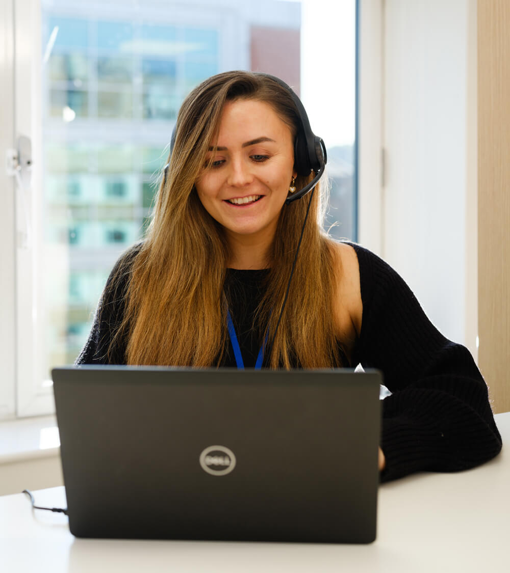 a smiling customer using their laptop in a bright office space