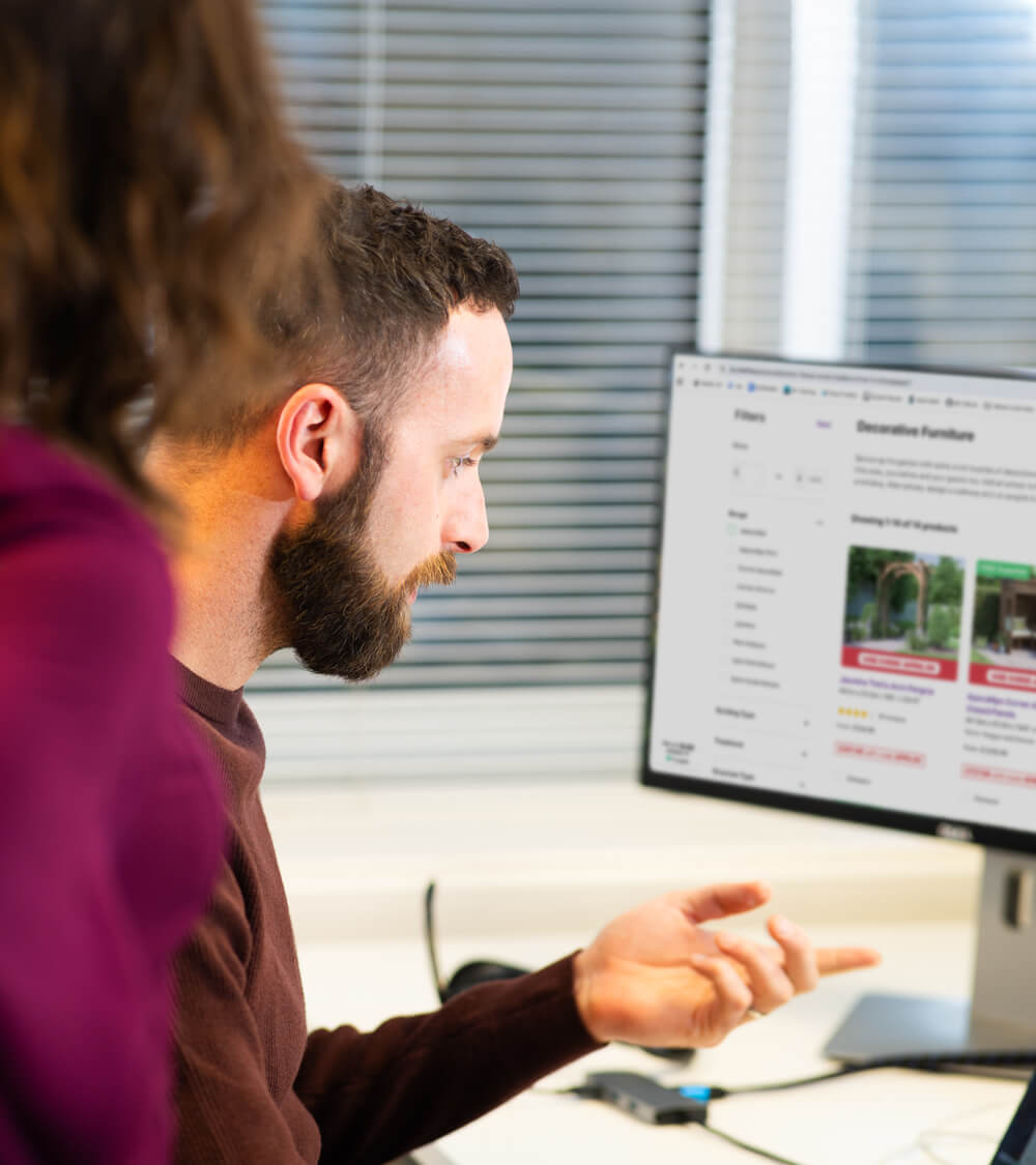 two developers looking at an ecommerce website on a computer screen