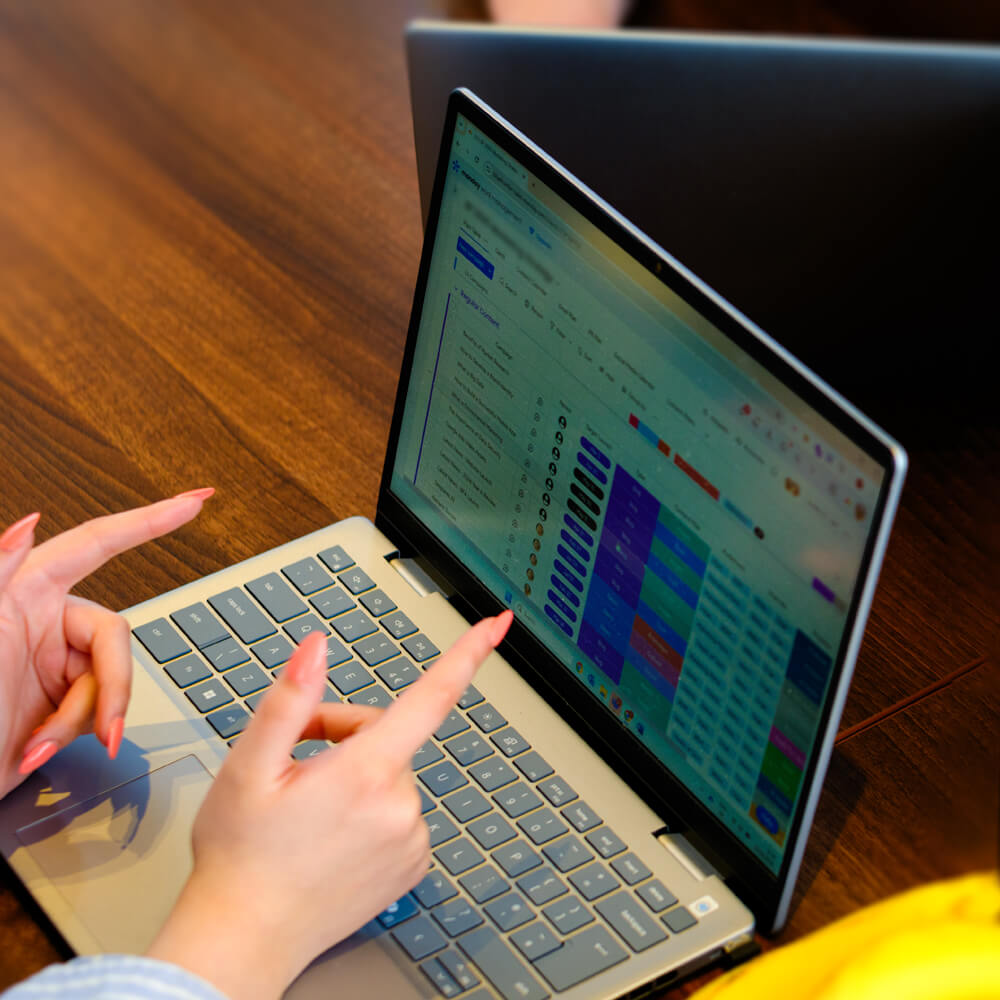 a project manager pointing to their laptop screen featuring a progress board