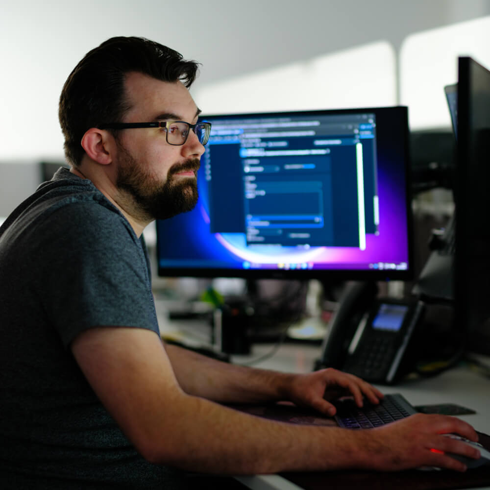 a developer looking at two monitors writing code