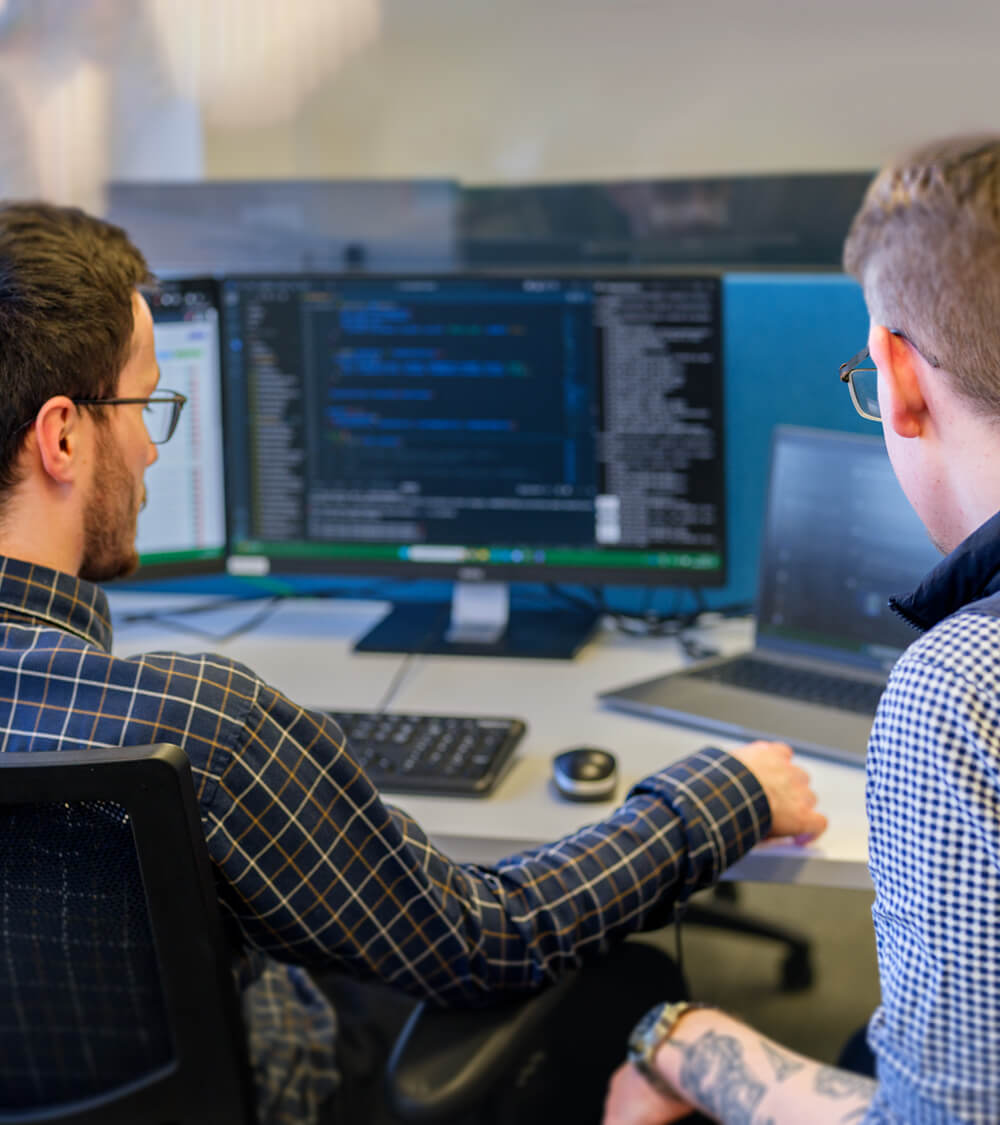 two developers analysing code on a computer monitor