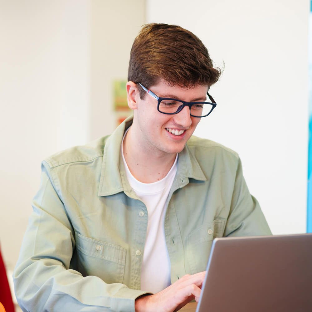 a customer smiling whilst using their laptop to shop online
