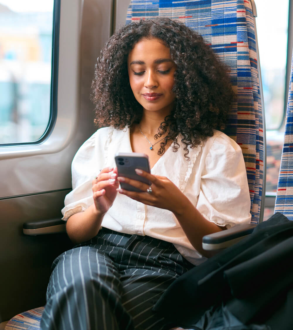 a woman sitting on an overground train in London using ChatGPT on her phone