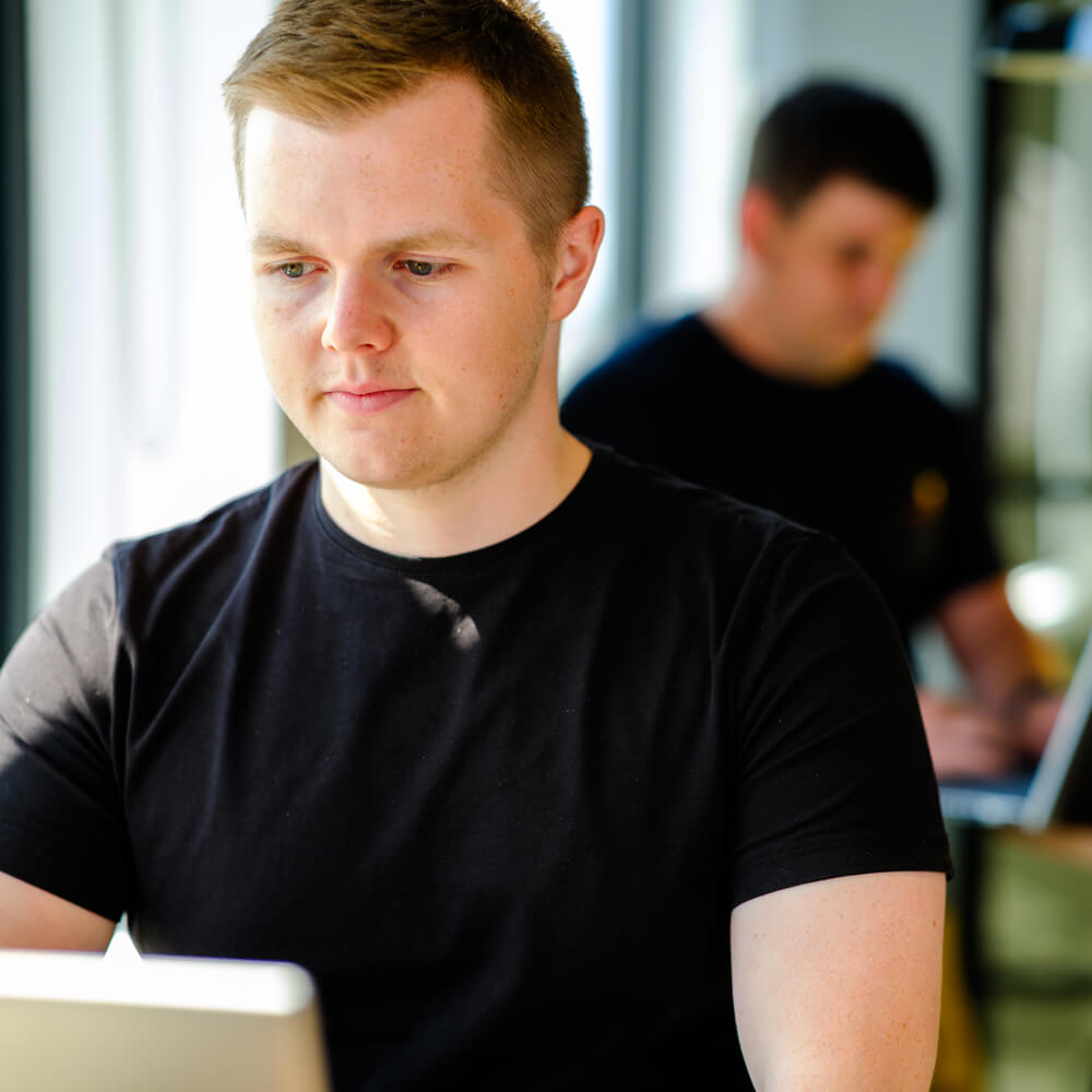 a digital marketer working on their laptop in a modern and bright office environment