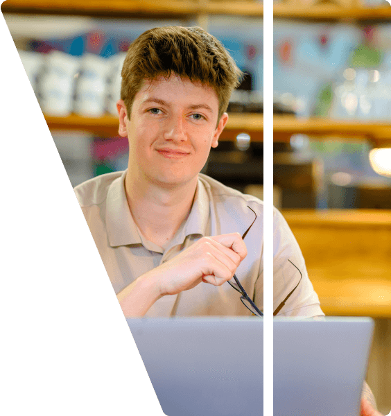 a digital marketer faces the camera with their laptop whilst holding their glasses