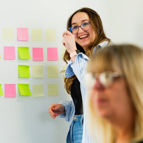 a colleague smiles whilst presenting their idea in front of a team