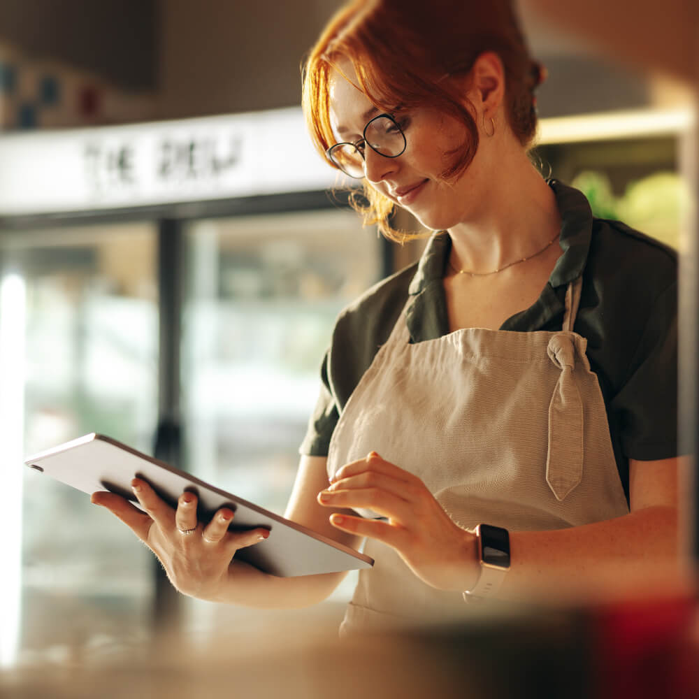 a young shop assistant using a tablet in a bakery