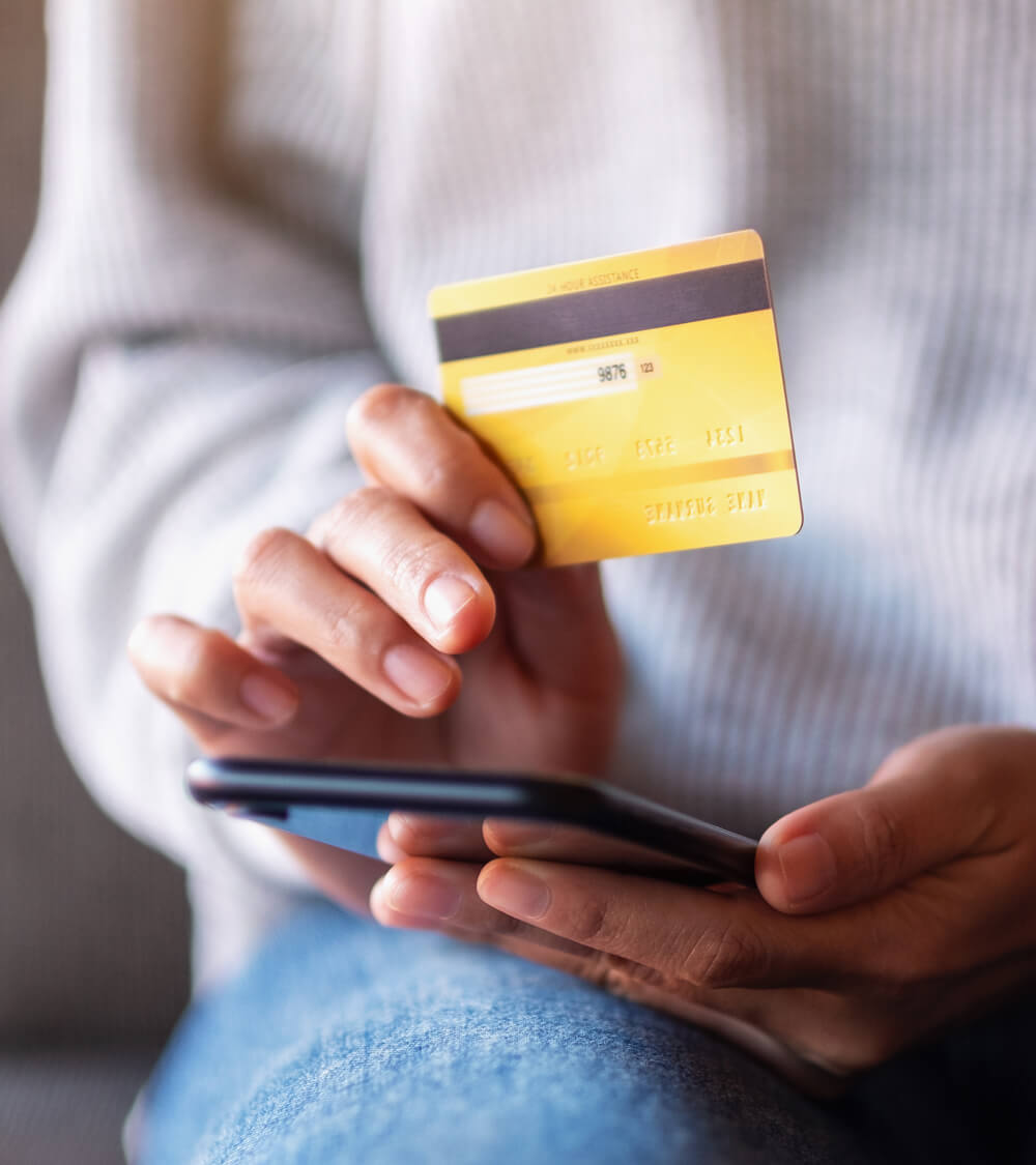 a woman entering her debit card details whilst using her phone