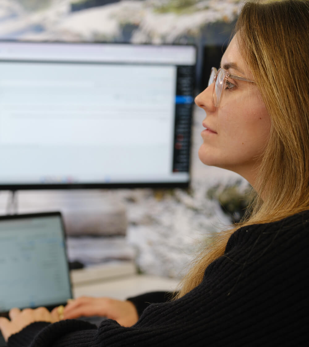 a cyber security expert analysing a customer's network on two computer monitors