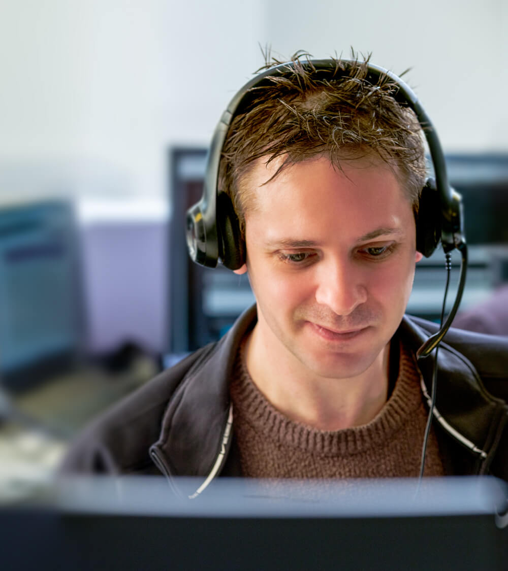 an IT engineer smiling as they speak to a customer using a headset