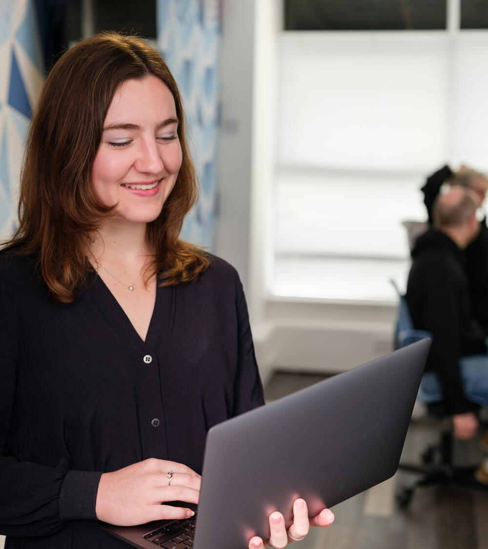 a manager smiles as they hold their laptop