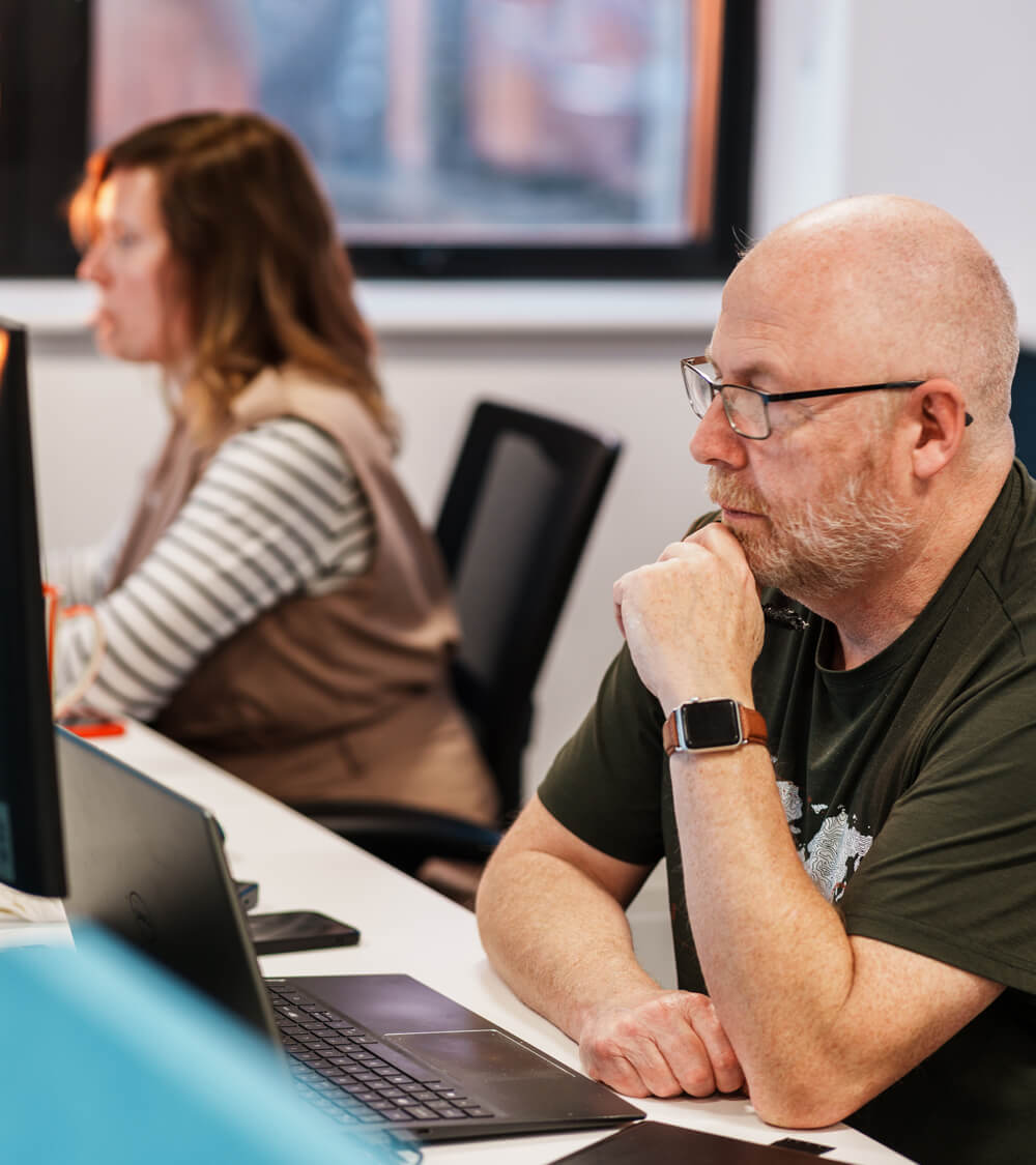 two coworkers sitting next to each other working on their computers